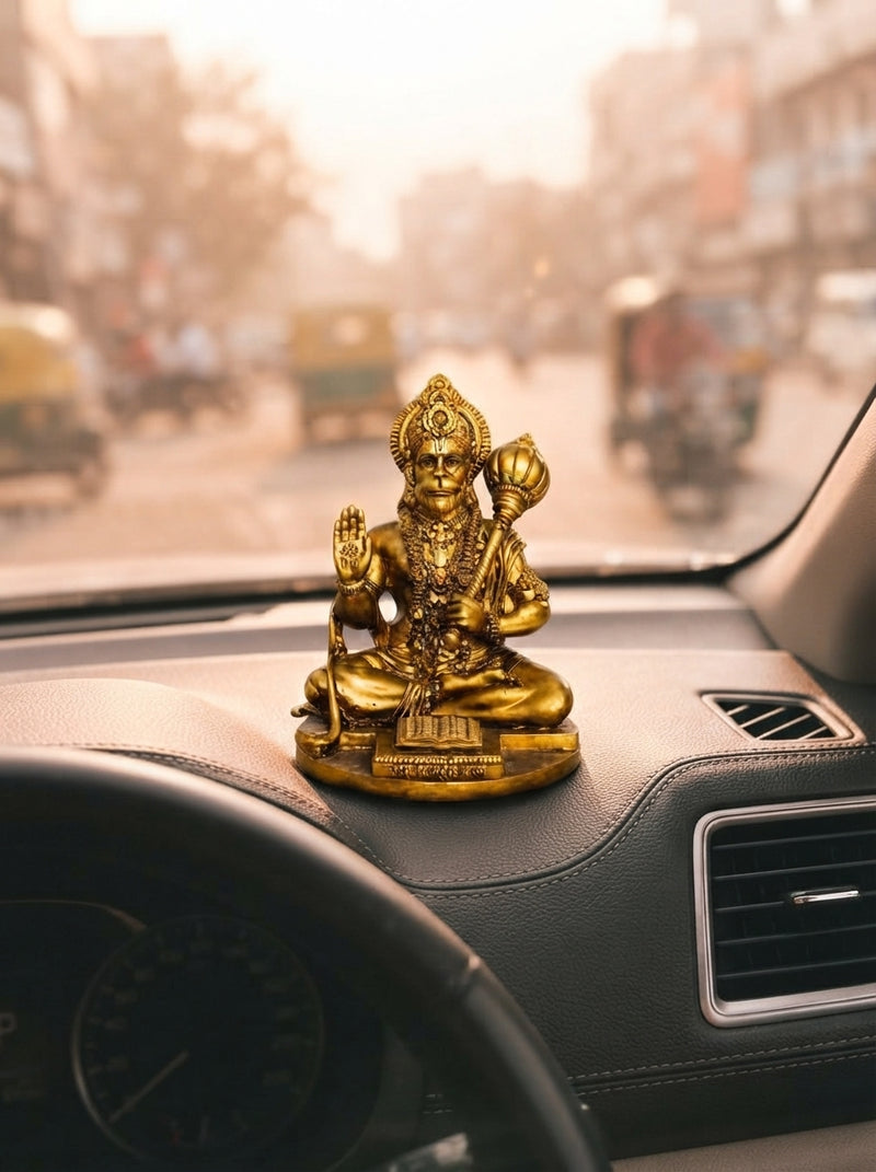 A detailed resin Hanuman Ji idol displayed on an SUV dashboard with a blurred urban background.
